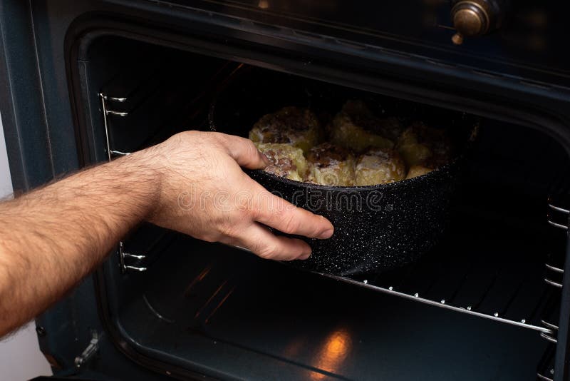 Hand puts potatoes in the oven. Male chef puts a tray of potatoes in the oven in the kitchen royalty free stock photo Hand puts potatoes in the oven. Male chef puts a tray of potatoes in the oven in the kitchen royalty free stock photo