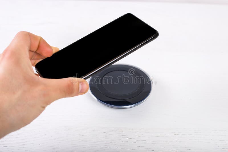 Hand putting mobile phone on wireless charger, modern equipment on white background royalty free stock image Hand putting mobile phone on wireless charger, modern equipment on white background royalty free stock image