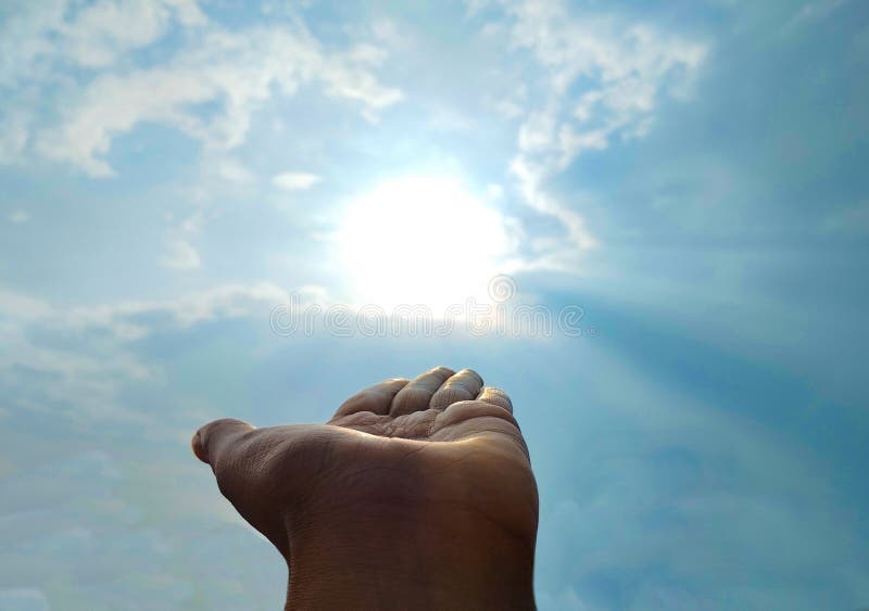 This powerful and artistic image shows an open hand extended toward the bright sun in a partially cloudy sky. The sun's rays beam down gently, creating a symbolic representation of hope, positivity, energy, and the human connection with nature. The composition evokes emotion and inspiration, ideal for themes of spirituality, ambition, dreams, and nature's power. Hand god reaching down sky man stock images, royalty-free photos and pictures