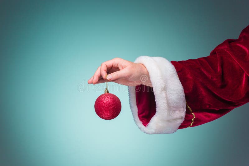 Hand Of Santa Claus Holding A Christmas Ball On Blue Background Stock ...