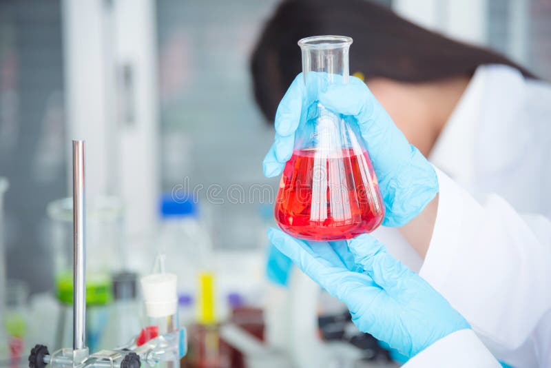 Hand of scientist holding flask with red color liquid stock photography