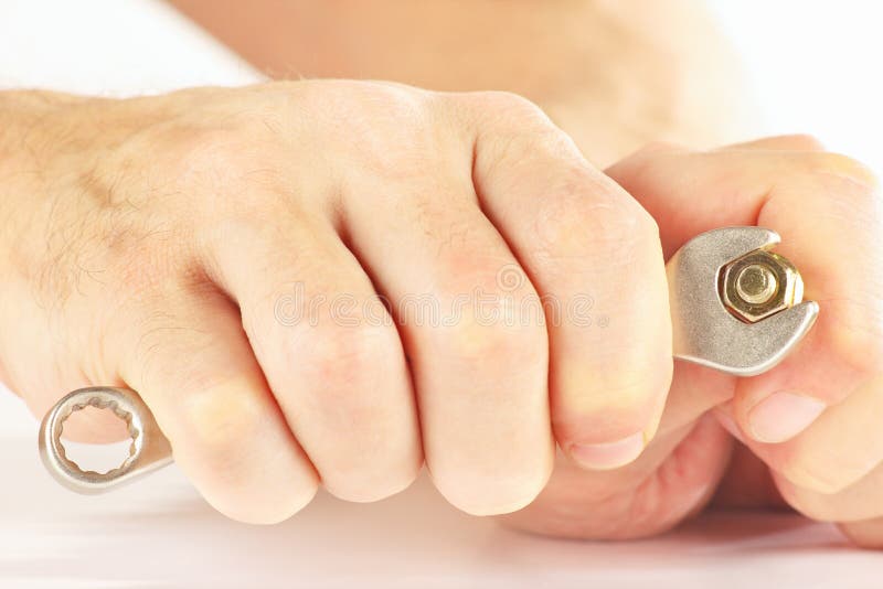 Hand of serviceman with spanner to tighten nut