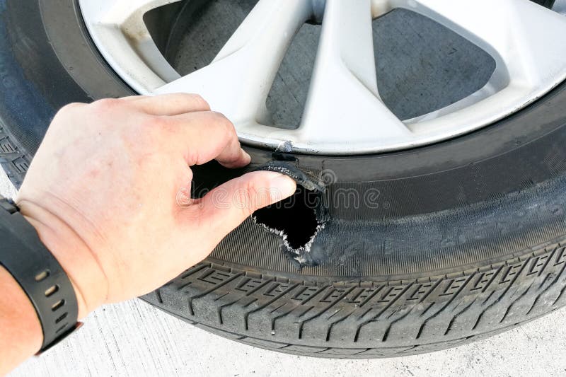 Hand showing flat ruptured damaged tire wheel with rim