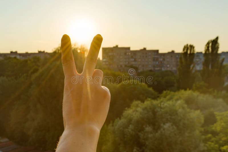 Hand showing two fingers or victory gesture. Background evening sunset, city silhouette stock photography Hand showing two fingers or victory gesture. Background evening sunset, city silhouette stock photography