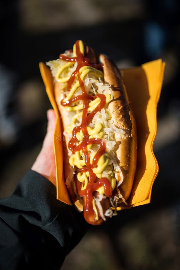 Hand som rymmer en wurstsmörgås arkivfoto Hand som rymmer en wurstsmörgås arkivfoto