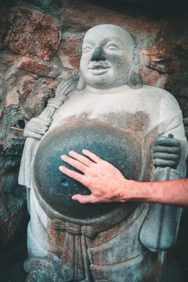 Hand som trycker på buken av en skratta buddha staty i Yonggungsa den buddistiska templet i Busan, Sydkorea royaltyfri foto Hand som trycker på buken av en skratta buddha staty i Yonggungsa den buddistiska templet i Busan, Sydkorea royaltyfri foto