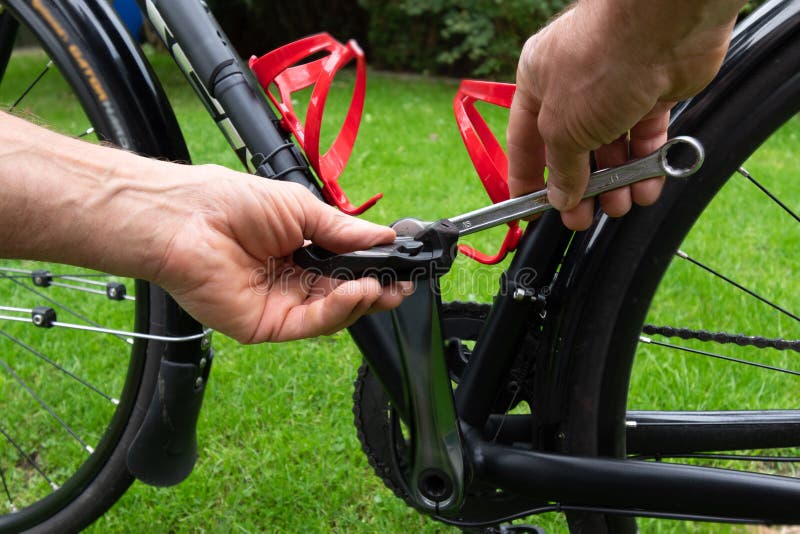 Hand with Spanner Attaching Bicycle Pedals To the Bike Stock Photo