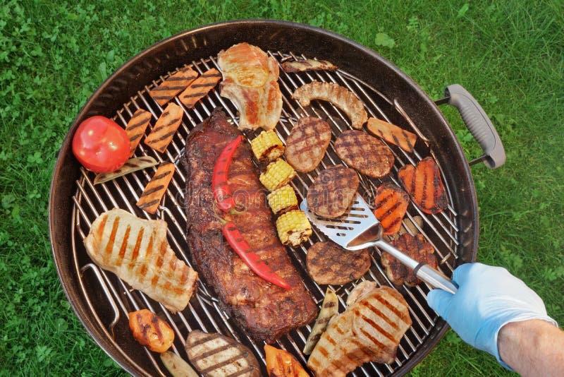 Hand with Spatula and BBQ Grill with Meat and Vegetables Stock
