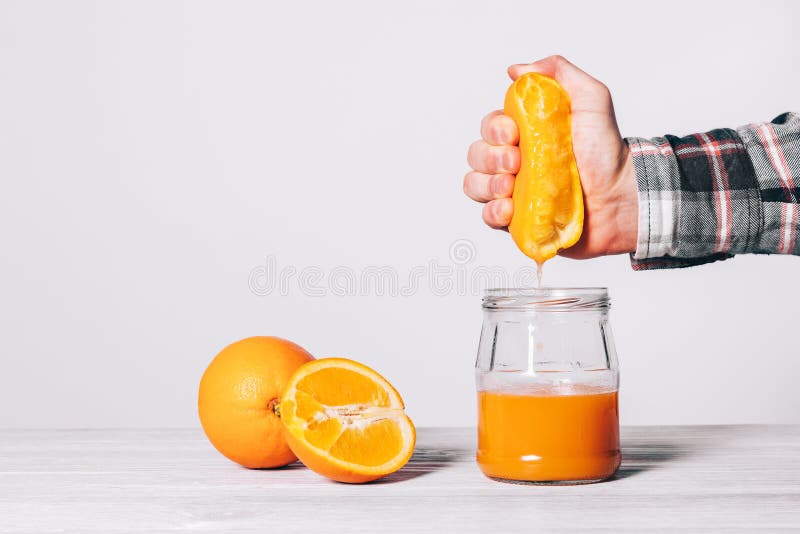 Mano apretando jugo naranja en vaso chirrido sobre el blanco,.