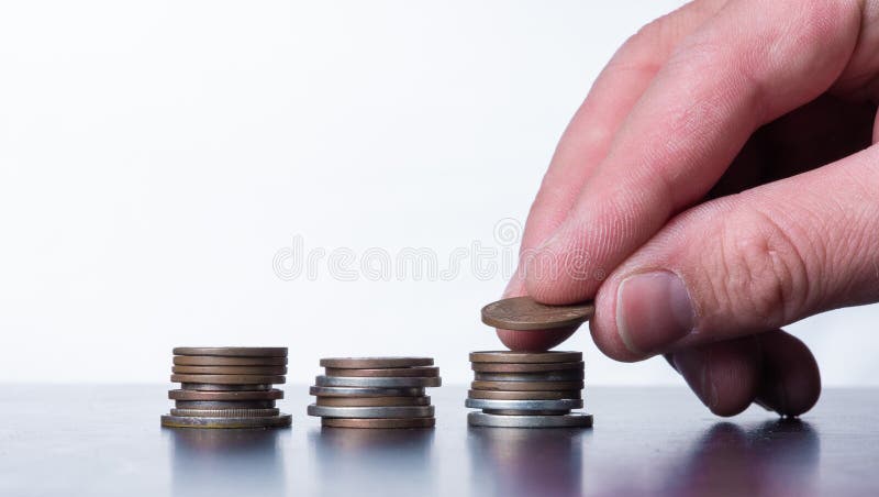 Hand stacking small coins on  a table stock images