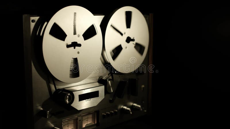 Hand starts playing vintage reel-to-reel recorder in dim light stock video