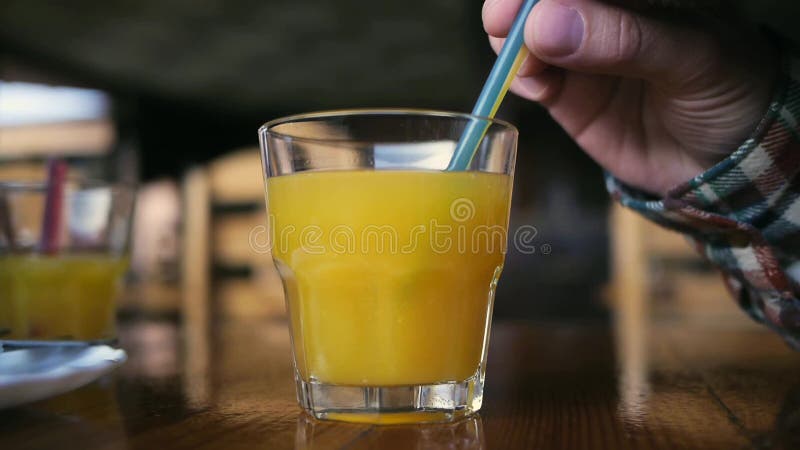 Hand stir in a glass of orange juice stock footage