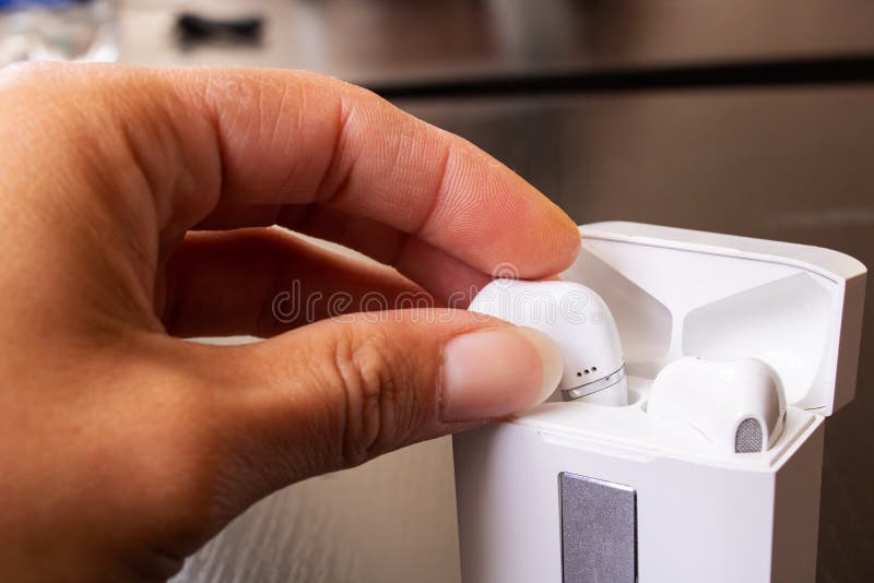 Hand takes out wireless earbuds close up. Hand takes out white wireless earbuds close up