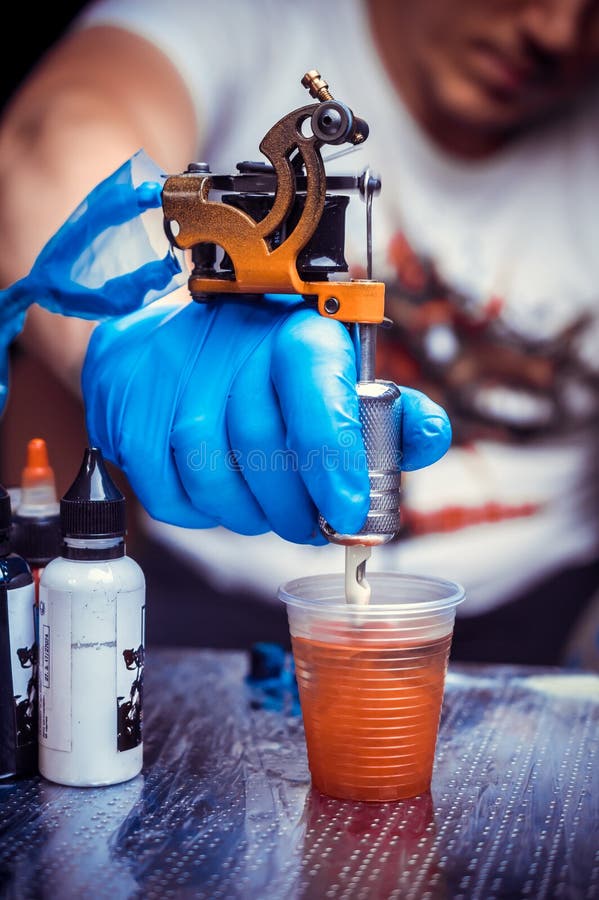 Hand of a Tattoo Artist with a Tattoo Gun. Stock Photo Image of