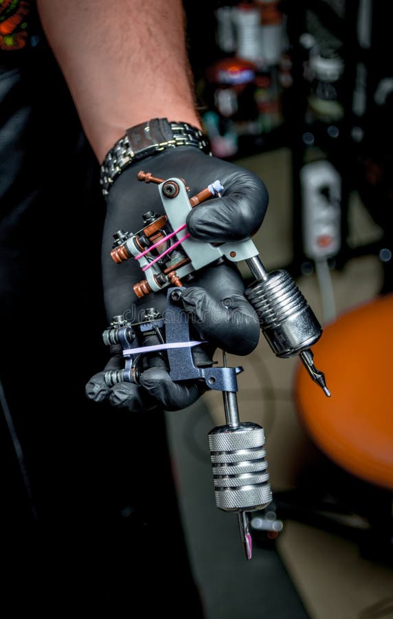 Hand of Tattoo Master and a Tattoo Machine. Stock Image Image of