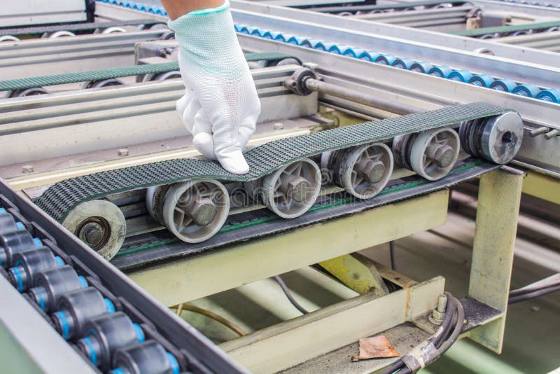 The hand of technician checking strength and tension of conveyor belt for maintenance