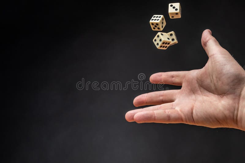 Hand throwing dice in front of a dark background