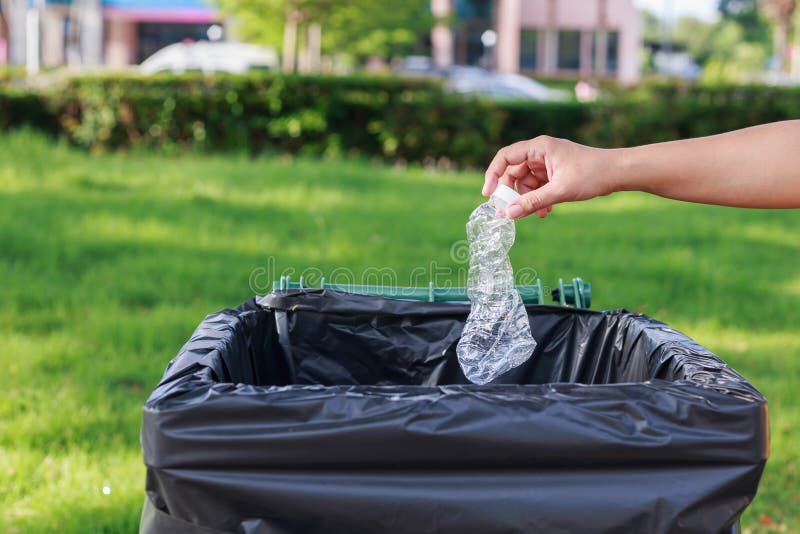 Hand throwing empty plastic bottle into the trash stock photos