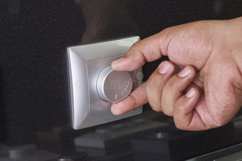 Hand Turning Down Electrical Light Dimmer Switch or Conditioner Heat Controller Stock Image