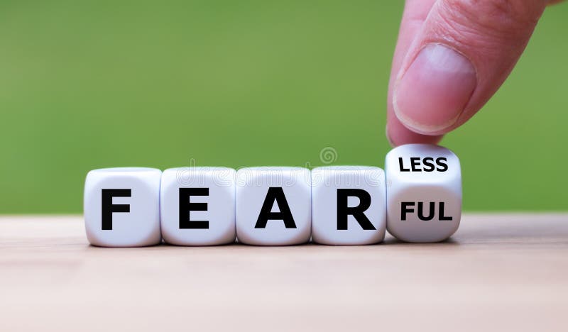 Hand turns a dice and changes the expression `fearful` to `fearless`.