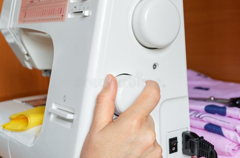 The Hand Turns the Wheel of the Sewing Machine To Adjust the Stitch