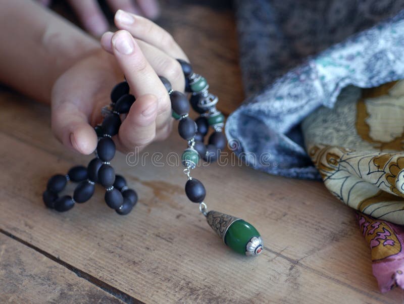 A long strand of exotic organic beads draped over a hand (model is lying on a wood floor), details of sustainable natural silk skirt shown.). A long strand of exotic organic beads draped over a hand (model is lying on a wood floor), details of sustainable natural silk skirt shown.)