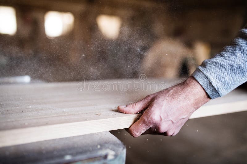 A hand of an unrecognizable man worker in the carpentry workshop, working with wood.