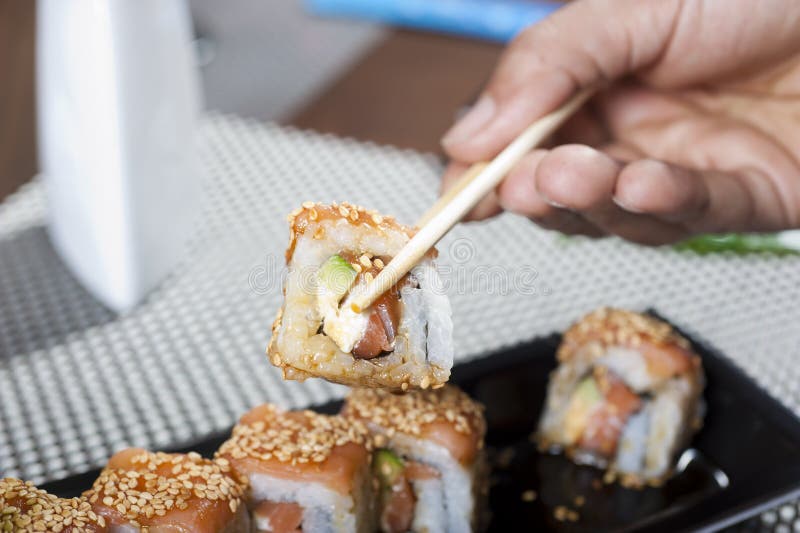Hand using chopsticks with sushi