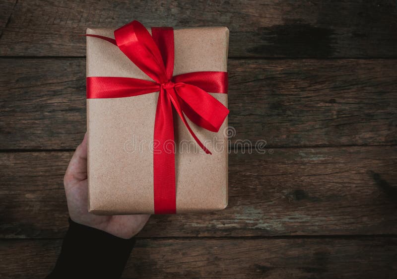 Hand van de bonus geeft de menselijke mens een huidige Bruine vlinderdas van de Giftdoos Rood lint op oude houten vrolijke Kerstm royalty-vrije stock foto Hand van de bonus geeft de menselijke mens een huidige Bruine vlinderdas van de Giftdoos Rood lint op oude houten vrolijke Kerstm royalty-vrije stock foto