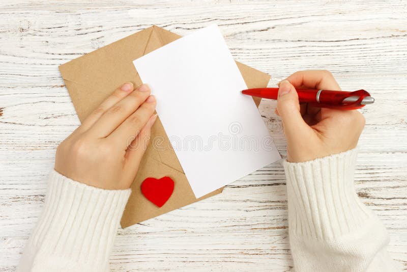Hand van meisje het schrijven liefdebrief op Valentine Day met de hand gemaakte prentbriefkaar De vrouw schrijft op prentbriefkaa