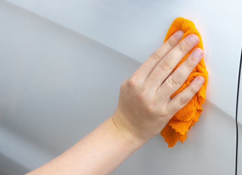 the hand washes the car with an orange cloth, manual washing of the car