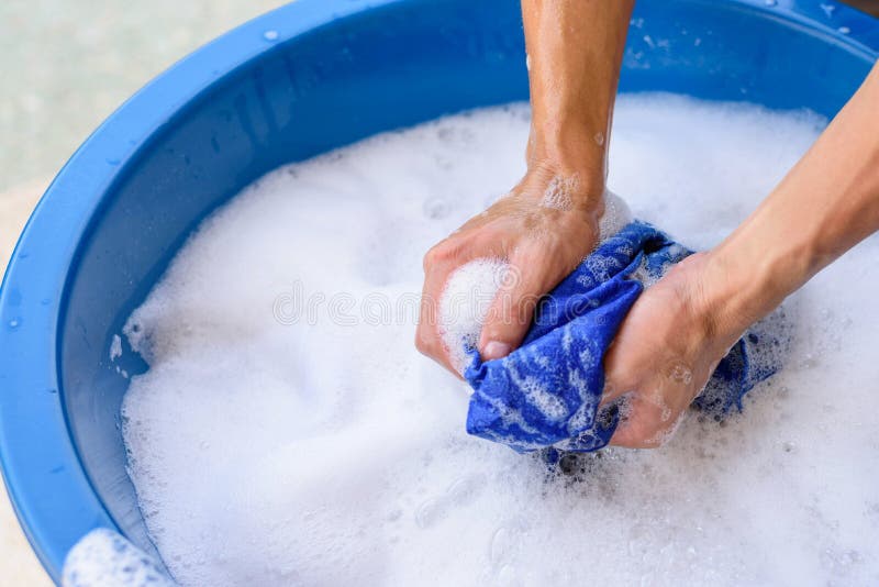 Hand washing clothes in Blue basin