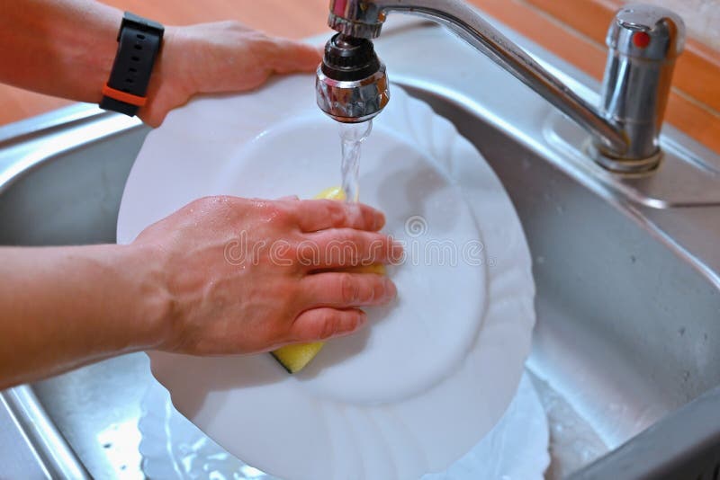 Hand Washing Dishes. Hand with Sponge and Sink in Kitchen Washing Dirty