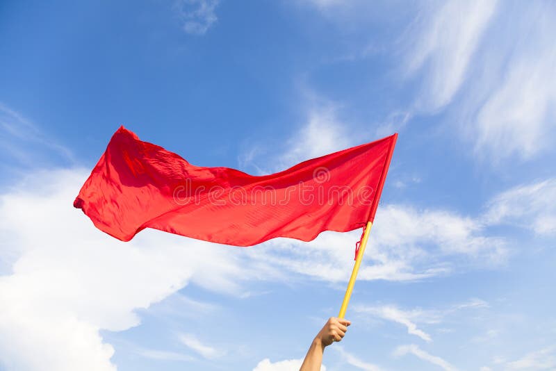 Hand waving a red flag with blue sky background