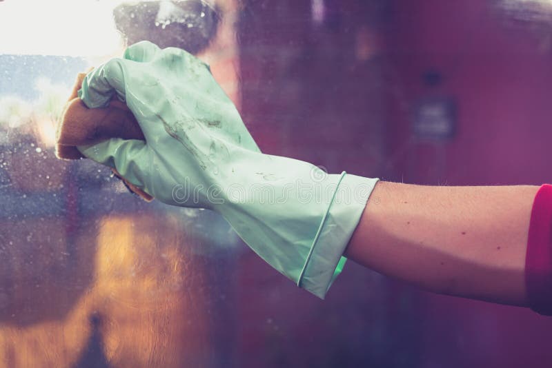 Hand wearing rubber glove is cleaning windows stock images