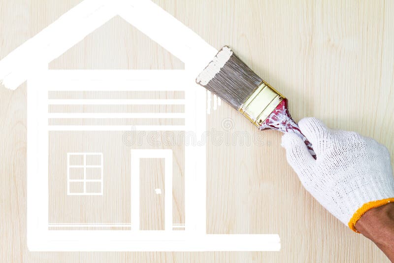 Man`s hand wearing white glove holding old grunge paintbrush and painting white house symbol on wooden wall