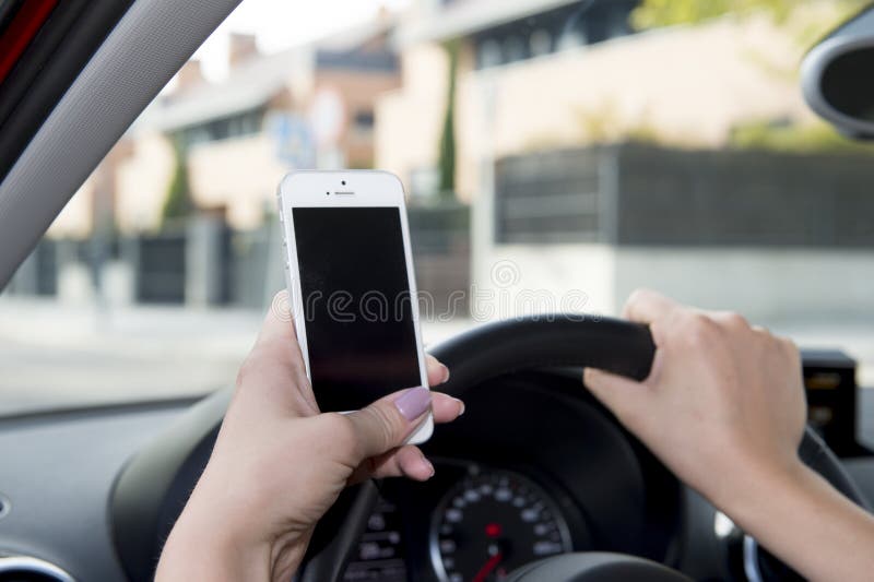 Hand of woman holding steering wheel and mobile phone driving car while texting distracted in risk