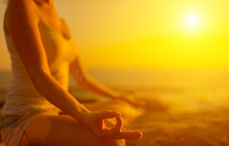 Ruka ženy meditácie v jogy predstavovať na pláži pri západe slnka.