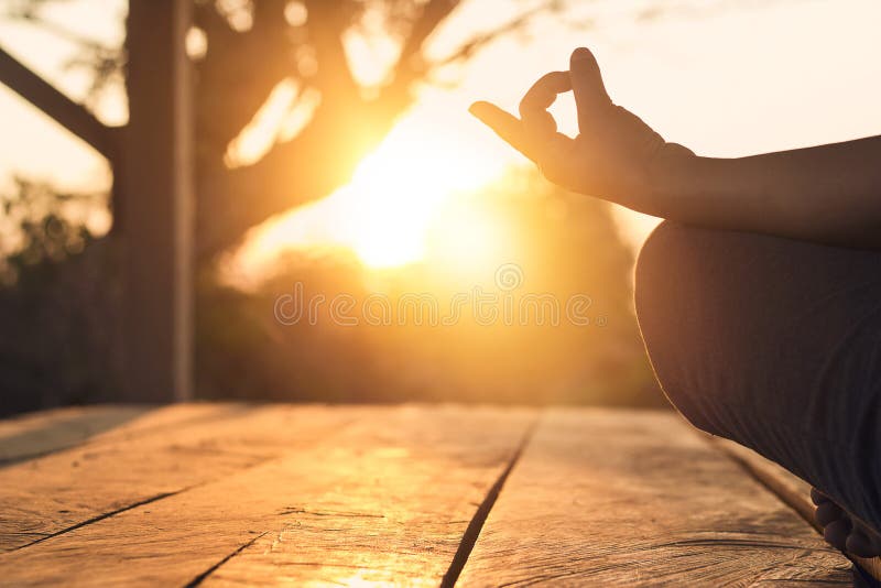 Hand of woman practicing meditation yoga on nature sunset