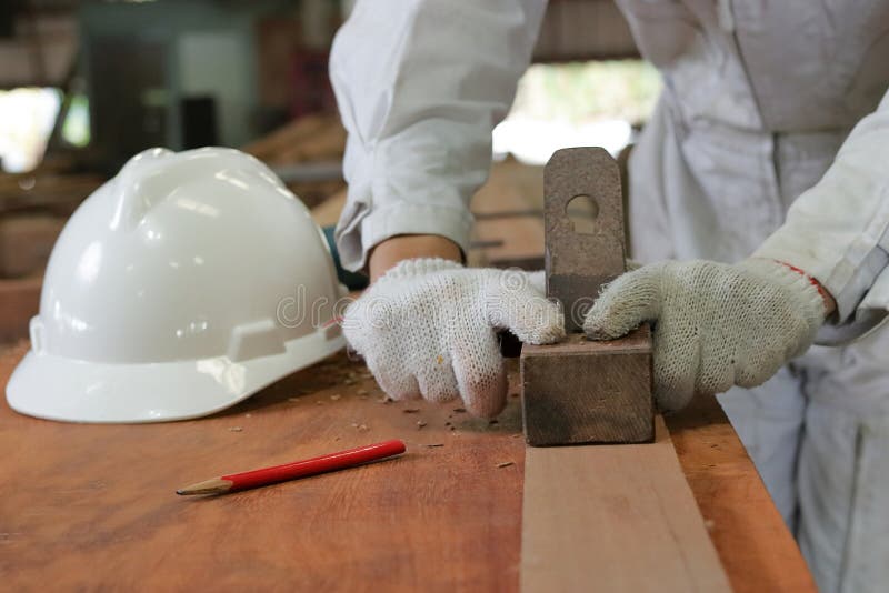 Hand of Worker Planing a Plank of Wood Using a Hand Planer in Carpentry Stock Image