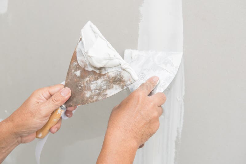 Hand of worker with plaster and trowel to gypsum board
