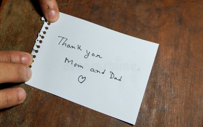 Hand written motivational word Thank you mom and dad. Men hand holding lifestyle motivational positive words written on a wooden background. Business, signs