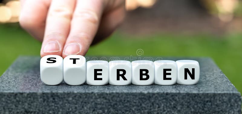 Hand turns dice and changes the German word 'Sterben' (die) to 'erben' (inherit. Hand turns dice and changes the German word 'Sterben' (die) to 'erben' (inherit