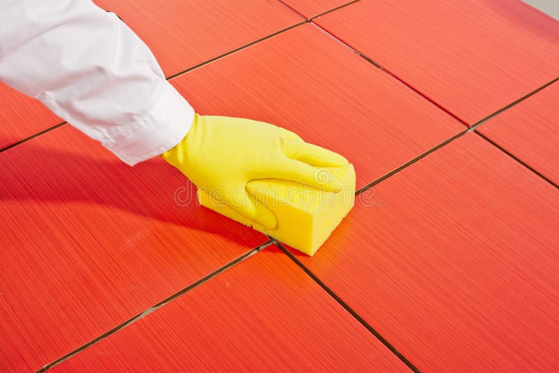 Hand with yellow gloves and sponge clean tiles
