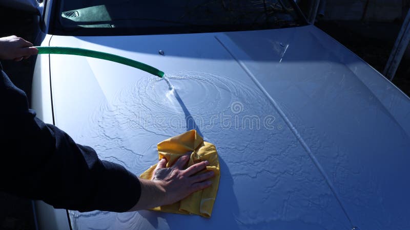 Textural movement of water on a clean hood of a gray car during washing by hand using a hose and a suede cloth to clean the vehicle from light dirt. Textural movement of water on a clean hood of a gray car during washing by hand using a hose and a suede cloth to clean the vehicle from light dirt