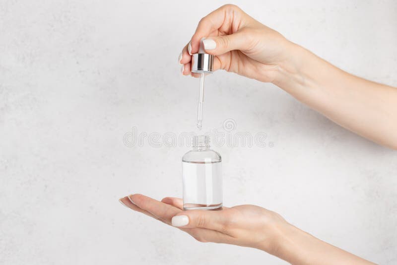 Hand of a young woman dripping a collagen moisturizer using a pipette.
