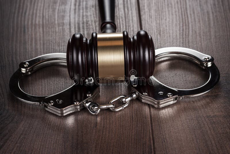 Handcuffs and judge gavel on brown wooden table stock images