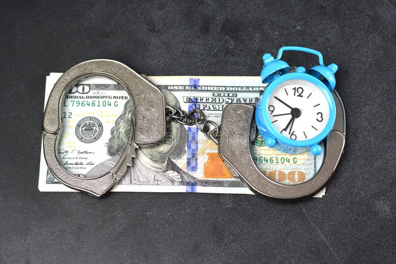 Handcuffs, money and alarm clock on dark background, bail concept