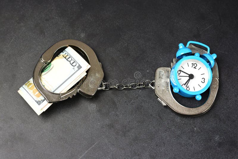 Handcuffs, money and alarm clock on dark background, bail concept