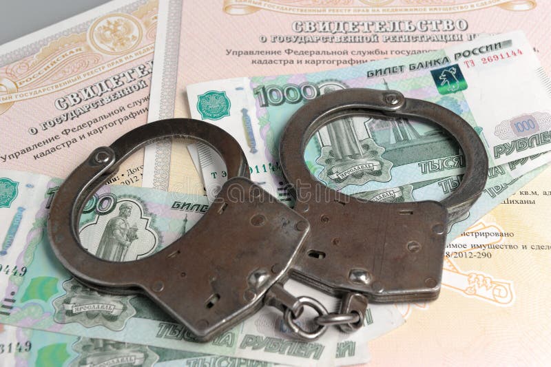 Handcuffs, money on the background of the ownership certificates